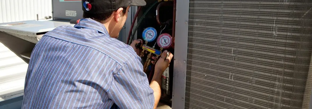 HVAC technician servicing a condenser unit in Poulsbo